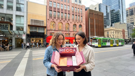 2 influencers with Mecca shipping box in front of a Mecca flagship store